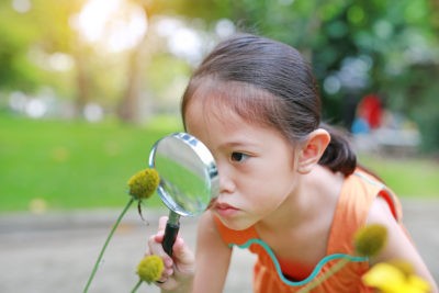 A girl looking through a magnifying glass.