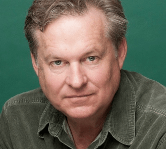 A headshot of a man wearing a green cotton shirt