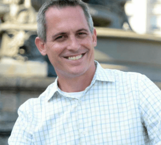 A headshot of a man in a white shirt